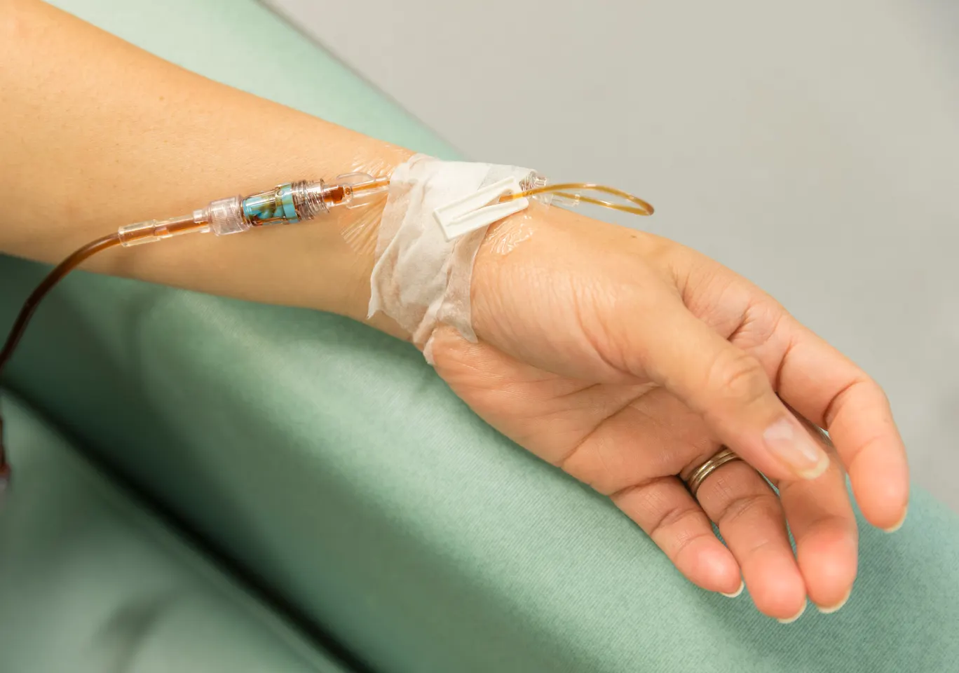 Kroplówki witaminowe Kościan: dłoń z wenflonem i linią infuzyjną na podkładzie